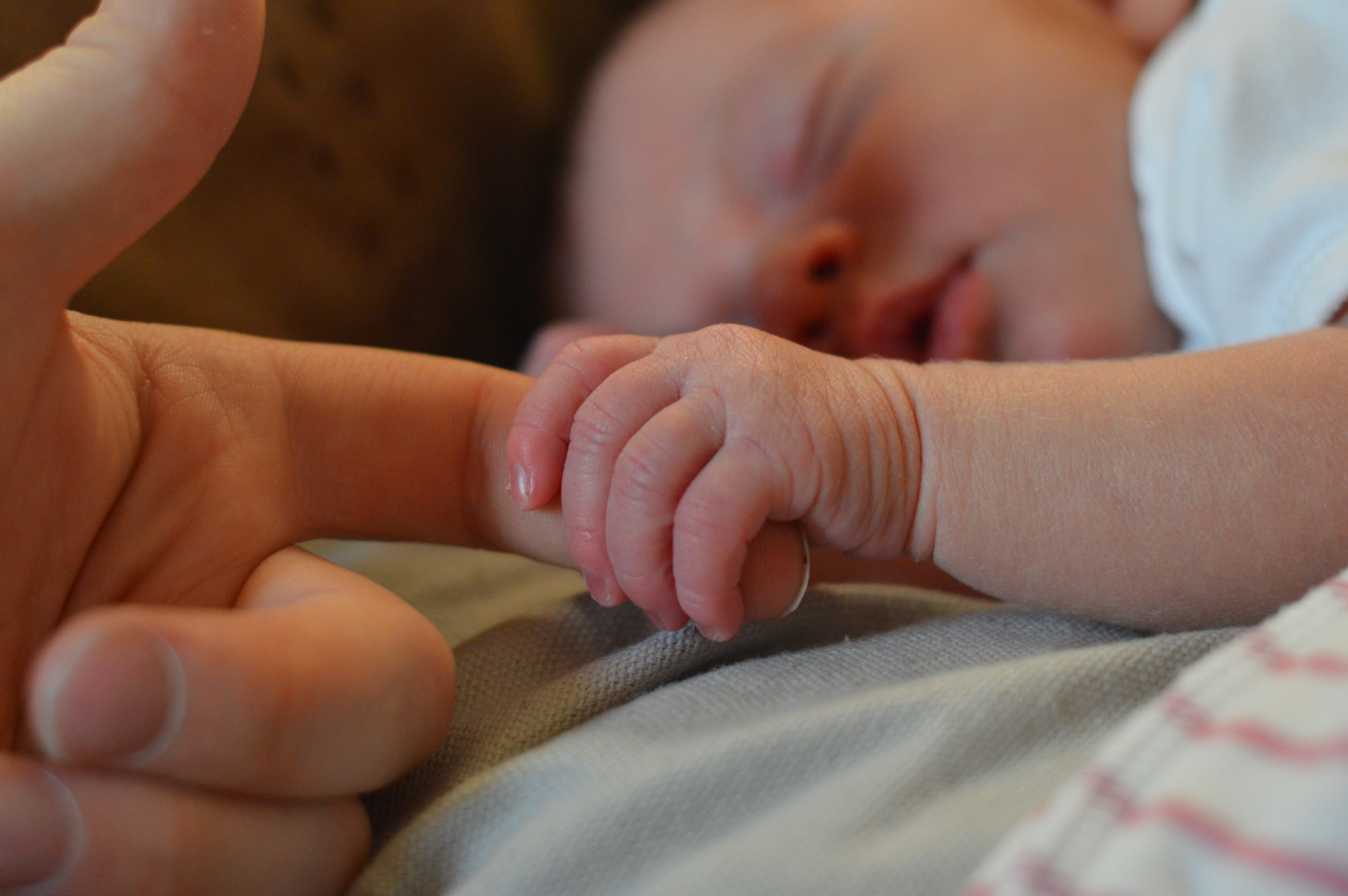 bébé qui dort en tenant le doigt de son parent
