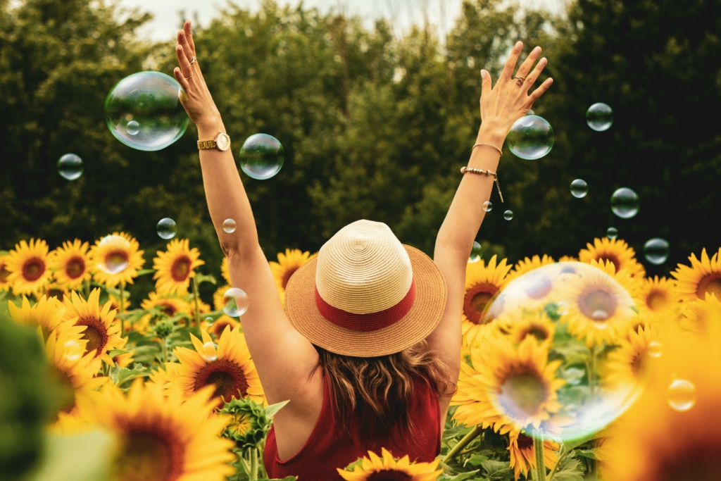 Femme dans un champs de tournesols les bras levés - bonheur soleil