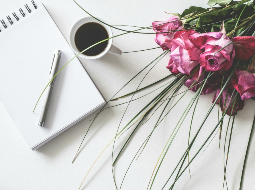 Photo avec un calepin, un stylo, une tasse de café et un bouquet de fleur allongé
