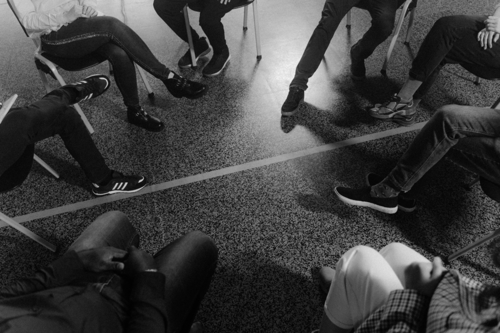 Image montrant les jambes de personnes assises en cercle, en thérapie de groupe