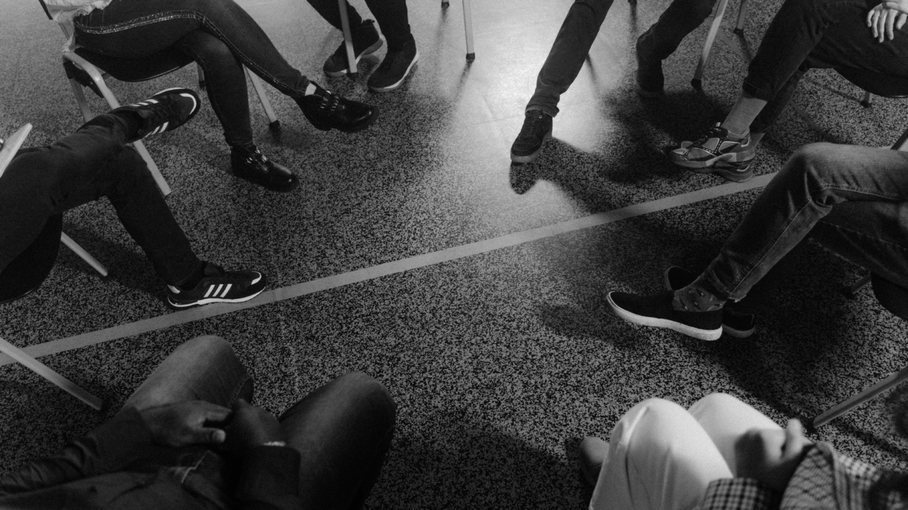 Image montrant les jambes de personnes assises en cercle, en thérapie de groupe