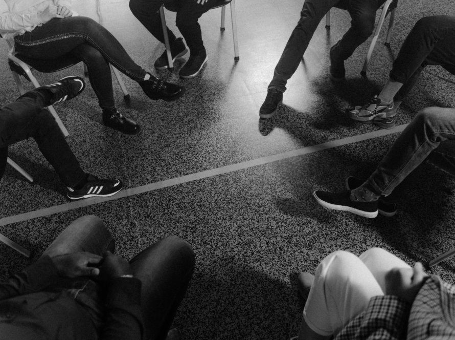 Image montrant les jambes de personnes assises en cercle, en thérapie de groupe